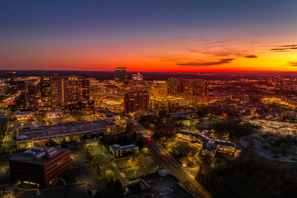 Aerial sunset view of Reston Town Center with glowing buildings and a colorful sky