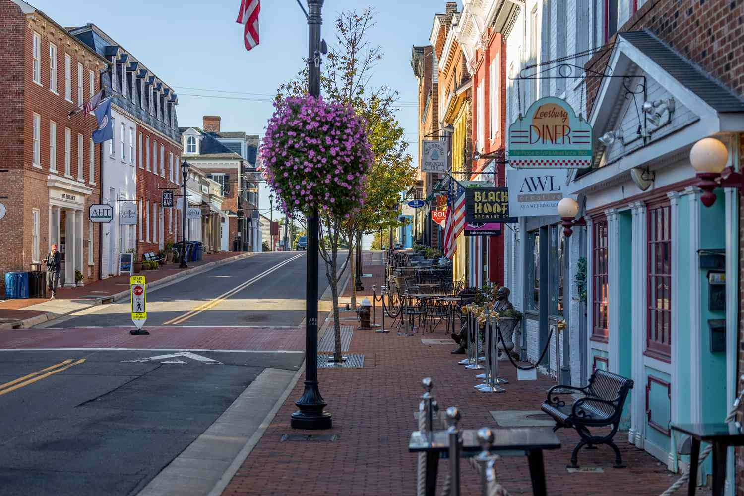 Historic downtown Leesburg street with brick sidewalks, colorful storefronts, and hanging flower baskets